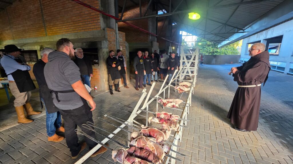 Frei Evandro Balestrin dá a bênção aos churrasqueiros voluntários que tornam o churrasco possível. Este ano foram quatro toneladas de carne comercializadas.